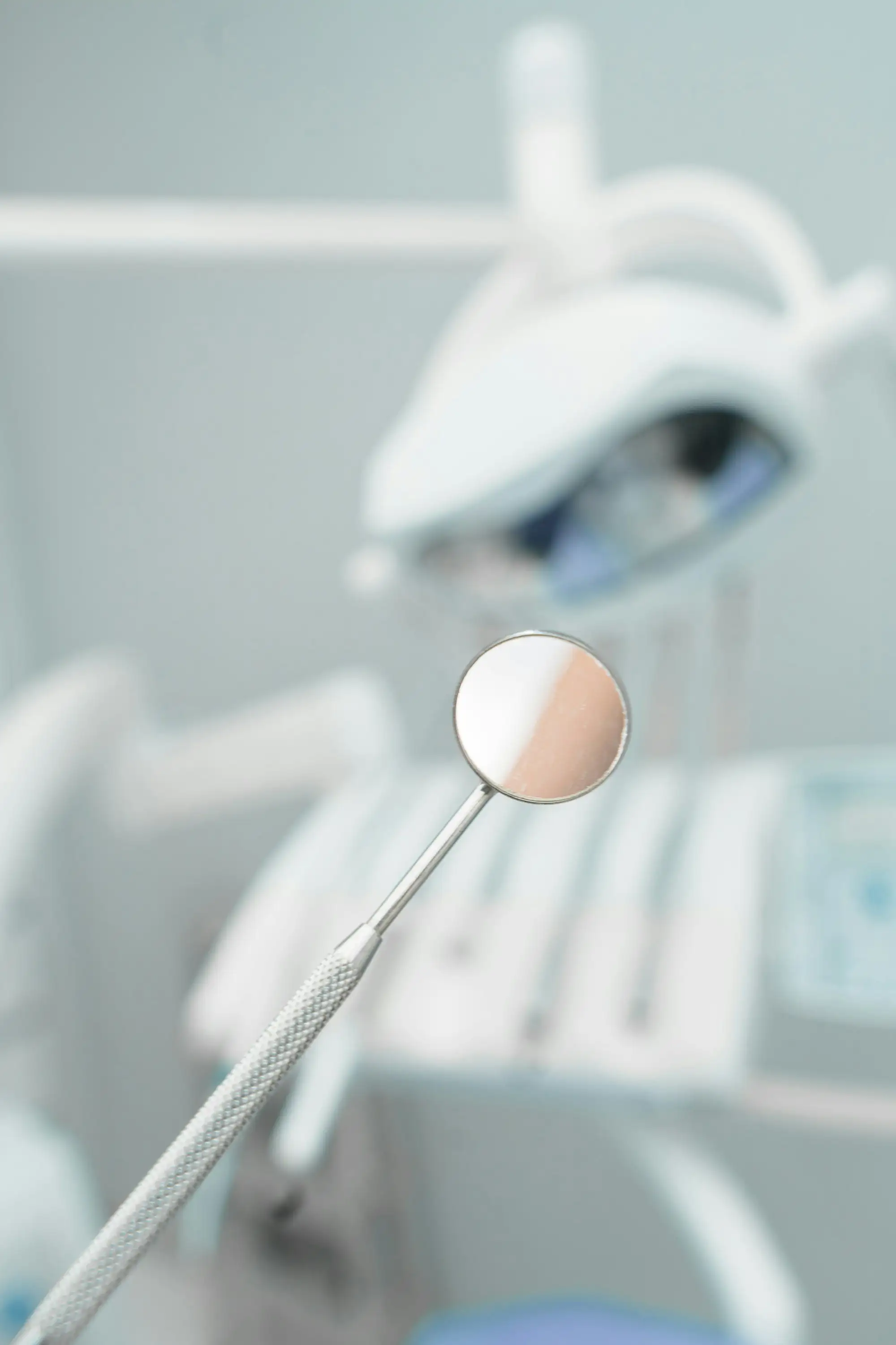 A dental mirror held up in a softly lit treatment room