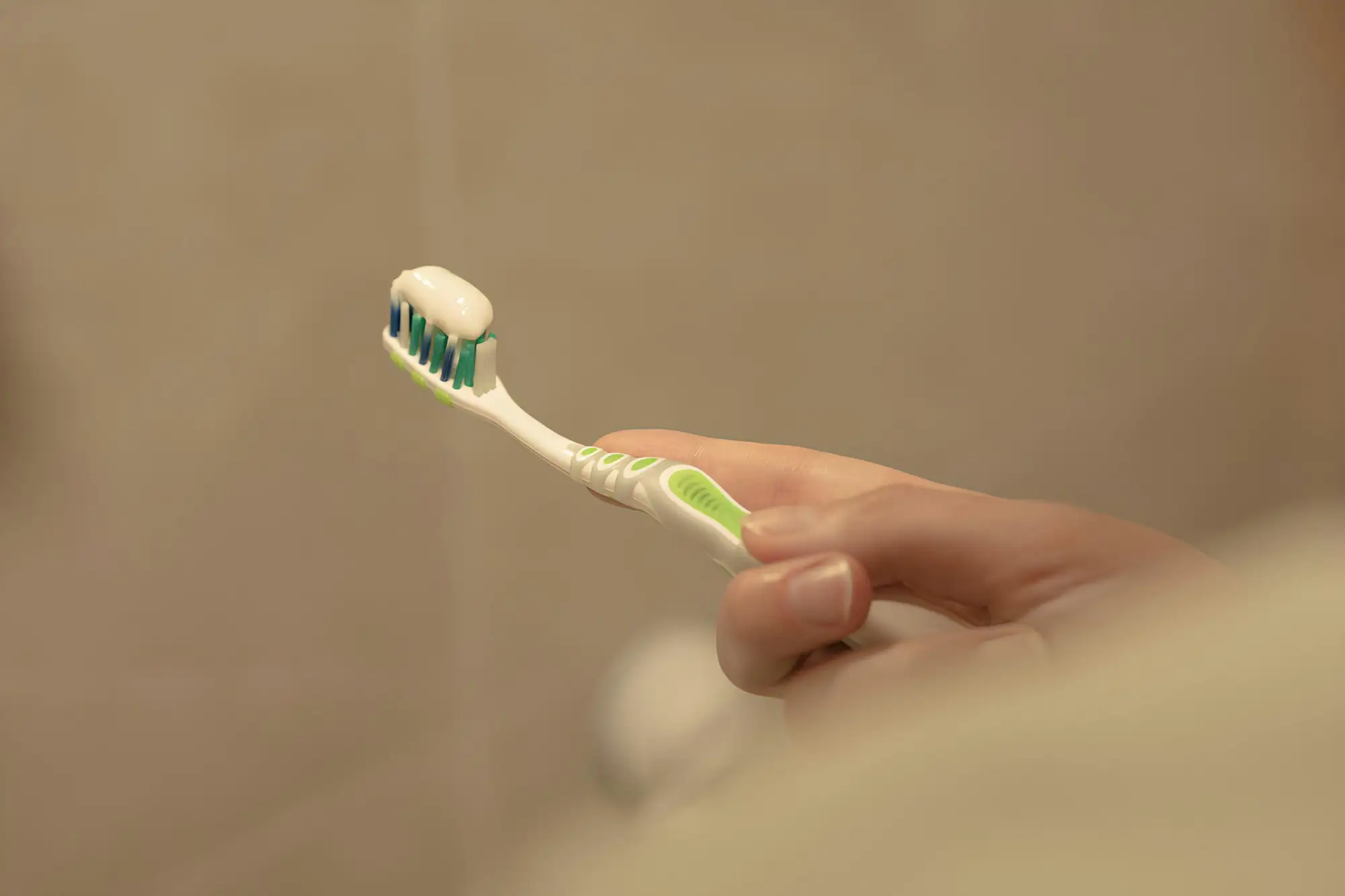 A hand holding a toothbrush with toothpaste on it