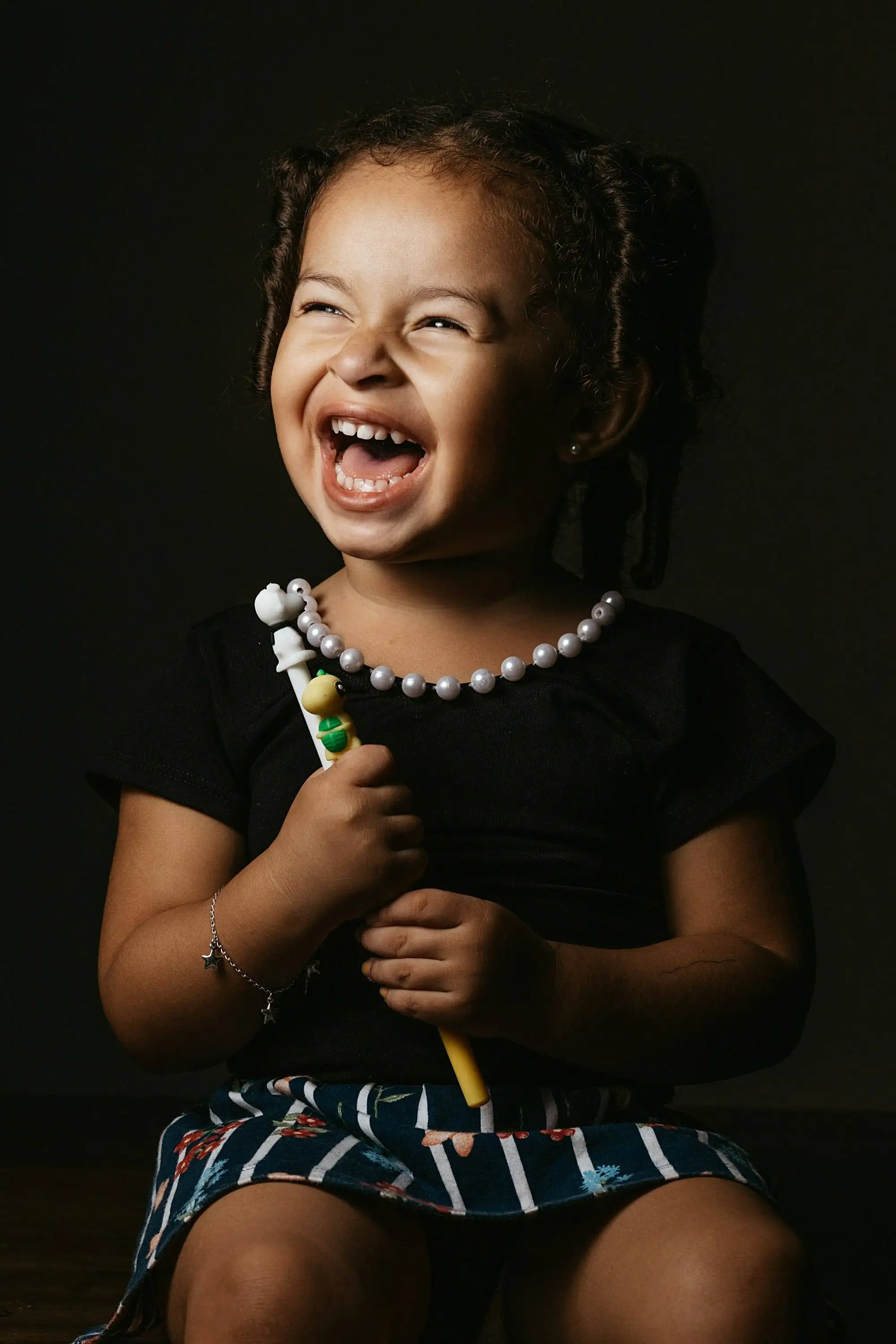 A laughing little girl holding a children's toothbrush with a small turtle on the handle